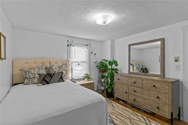 bedroom with light hardwood / wood-style floors and a textured ceiling