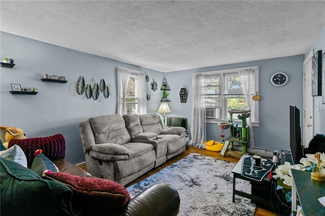 living room featuring hardwood / wood-style floors, cooling unit, and a textured ceiling