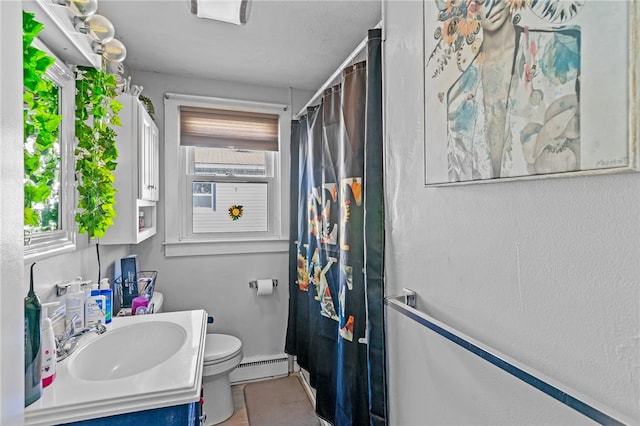 bathroom with vanity, toilet, a wealth of natural light, and a baseboard heating unit