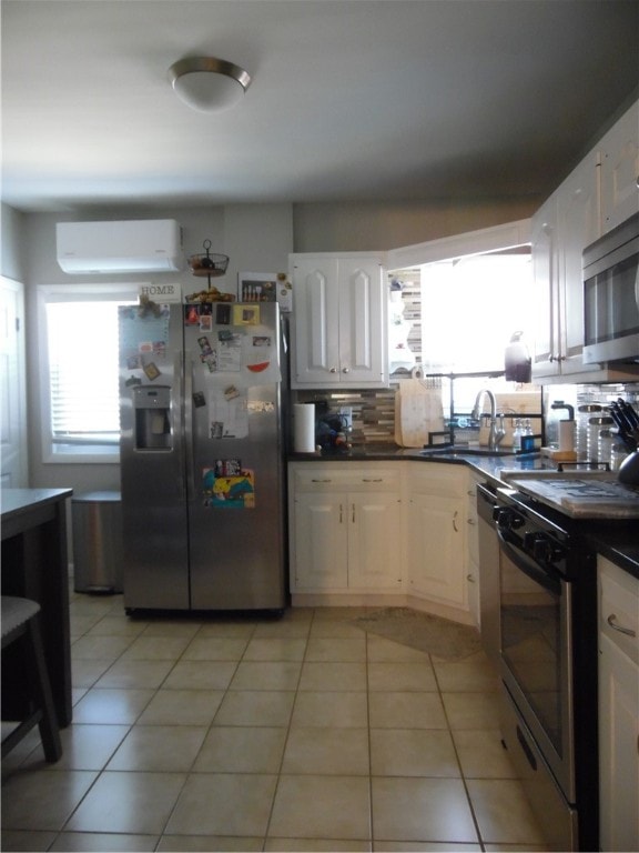 kitchen featuring white cabinetry, appliances with stainless steel finishes, a wall unit AC, and light tile patterned floors