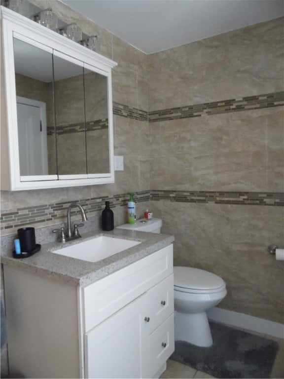 bathroom with tile walls, toilet, vanity, and tasteful backsplash