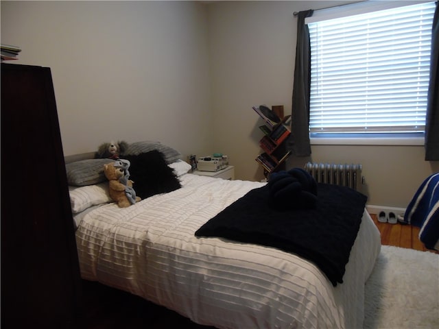 bedroom with radiator heating unit and hardwood / wood-style floors