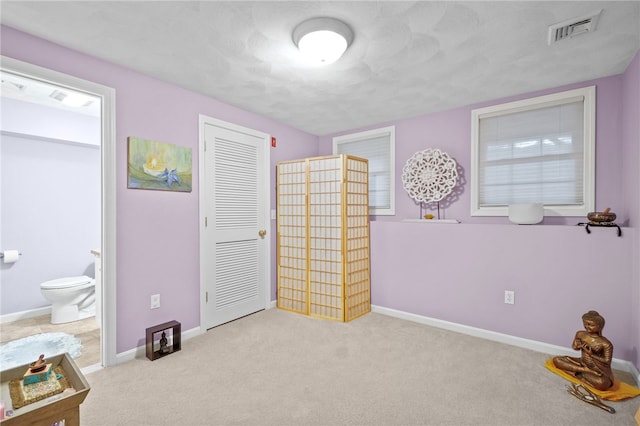 carpeted bedroom with ensuite bathroom and a closet