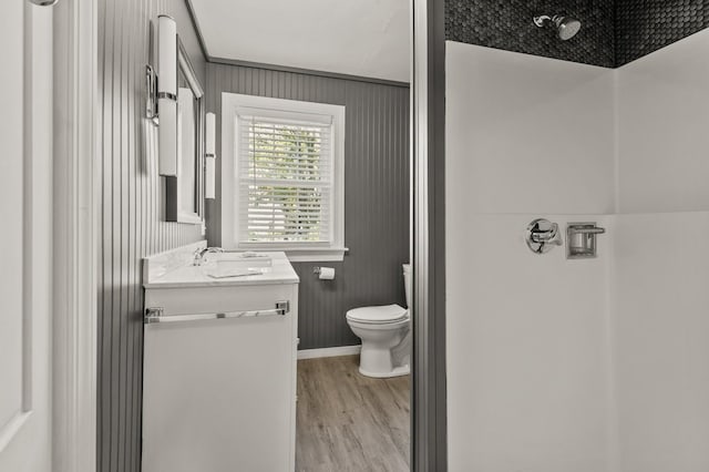 bathroom with hardwood / wood-style floors, wood walls, vanity, and toilet