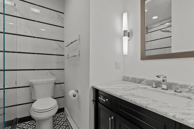 bathroom featuring toilet, vanity, tile patterned floors, and tiled shower