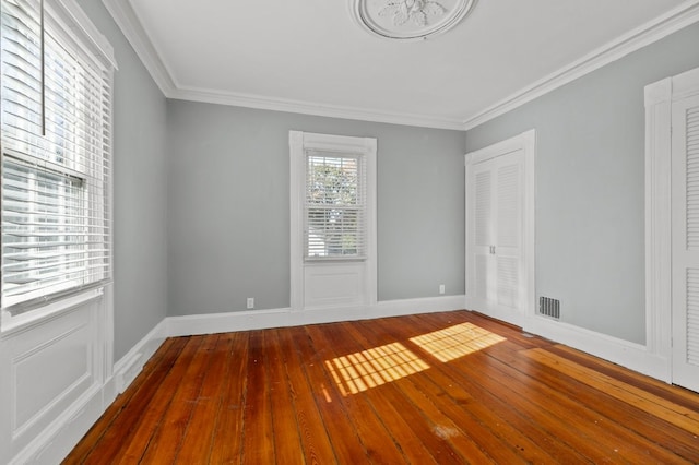 spare room with hardwood / wood-style flooring, crown molding, and plenty of natural light