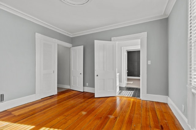 unfurnished bedroom with hardwood / wood-style floors, a closet, and crown molding