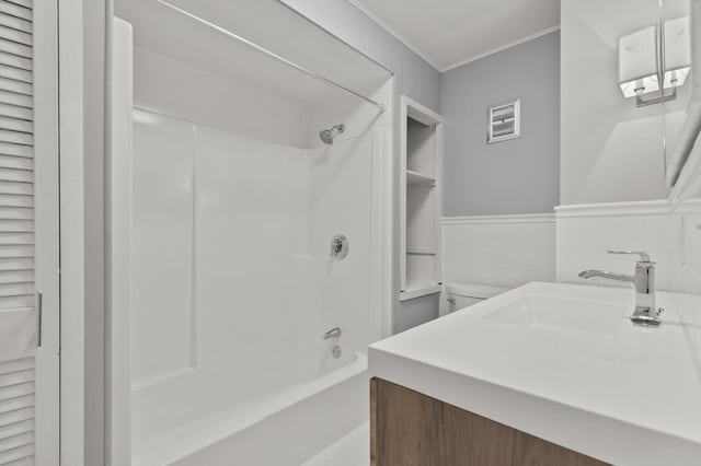 full bathroom with tile walls, vanity, crown molding, toilet, and shower / bathtub combination