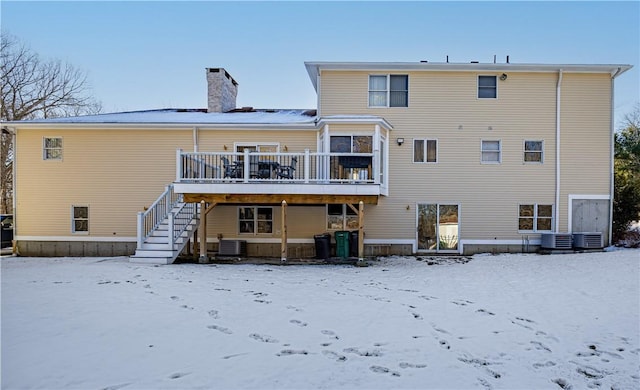 snow covered rear of property with central AC and a deck