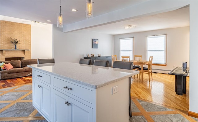 kitchen with a fireplace, a kitchen island, hanging light fixtures, and a breakfast bar area