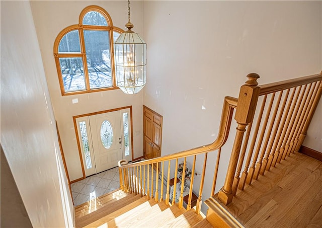 foyer entrance featuring light tile patterned flooring, a high ceiling, and a notable chandelier