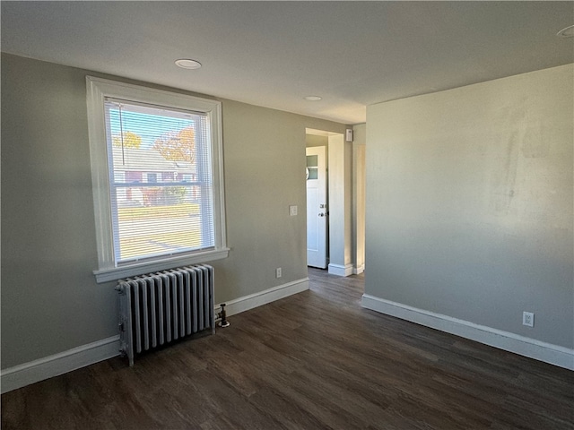 unfurnished room featuring dark wood-type flooring and radiator heating unit