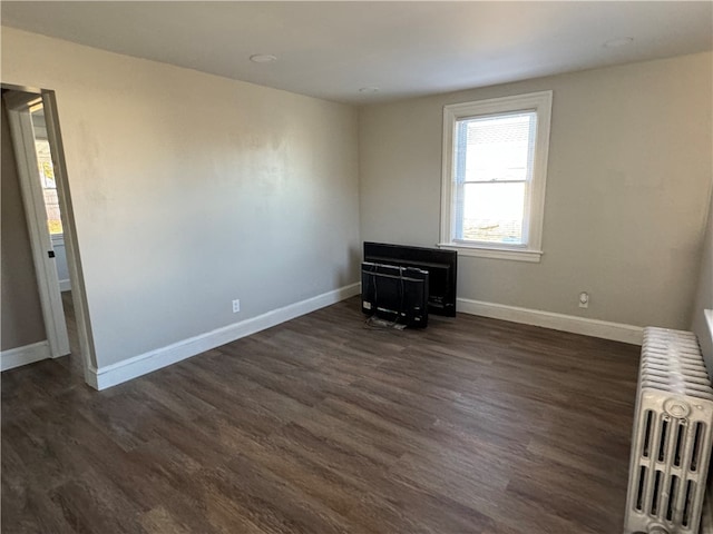 empty room with dark hardwood / wood-style floors and radiator heating unit