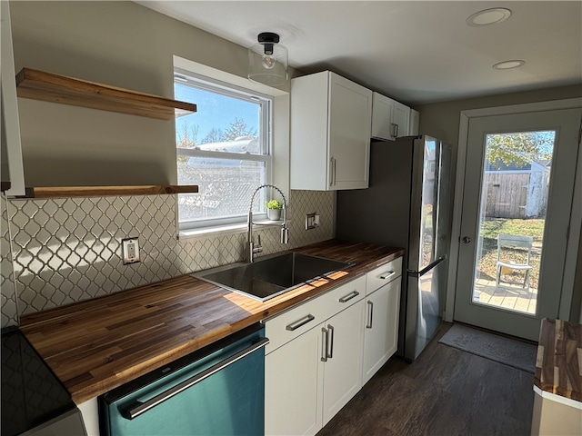 kitchen with sink, dark hardwood / wood-style floors, wood counters, white cabinetry, and appliances with stainless steel finishes