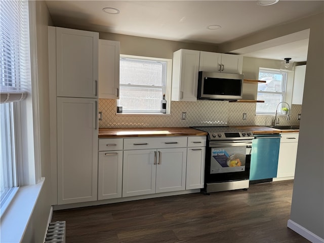 kitchen with stainless steel appliances, white cabinetry, backsplash, dark hardwood / wood-style flooring, and sink