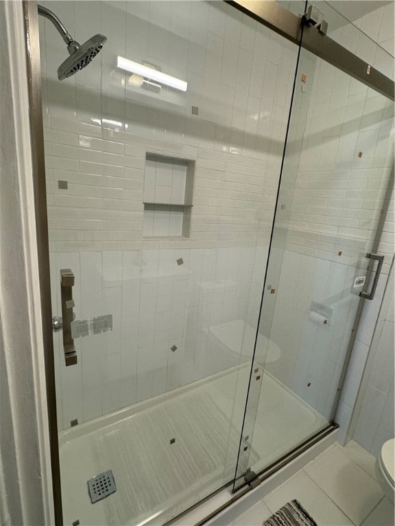 bathroom featuring a shower with door and toilet