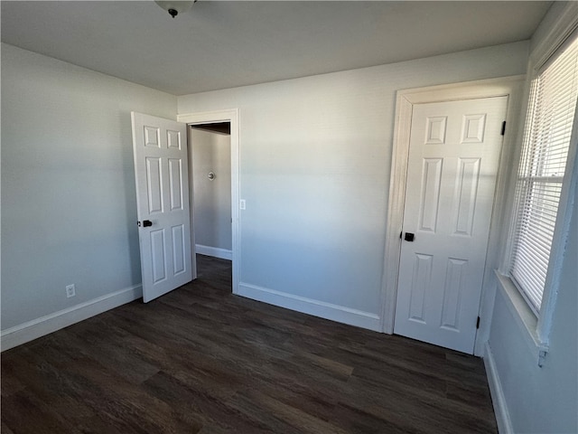 unfurnished bedroom with dark hardwood / wood-style flooring and a closet