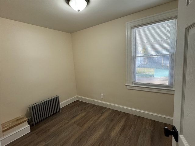 spare room with dark wood-type flooring and radiator