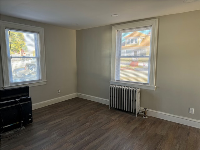 empty room featuring radiator and dark hardwood / wood-style flooring