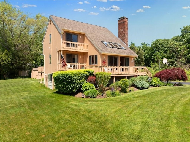 back of house with a yard, a balcony, and a wooden deck