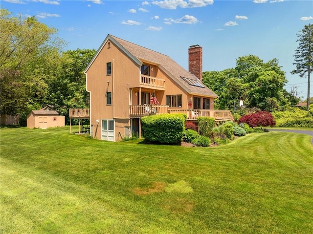 back of house with a lawn, a wooden deck, a balcony, and a shed