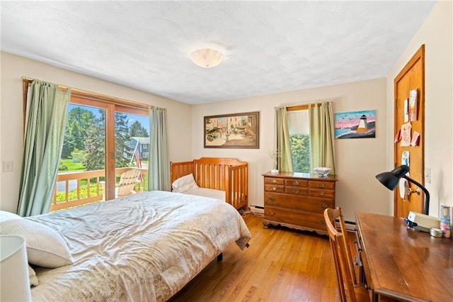 bedroom with access to exterior, hardwood / wood-style floors, and a baseboard radiator