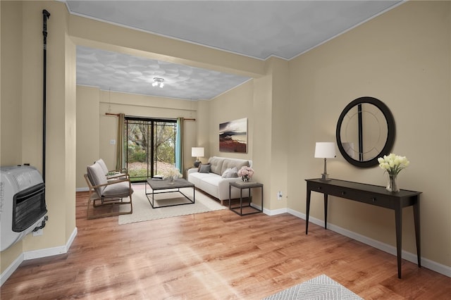 living room featuring light wood-type flooring, heating unit, and crown molding