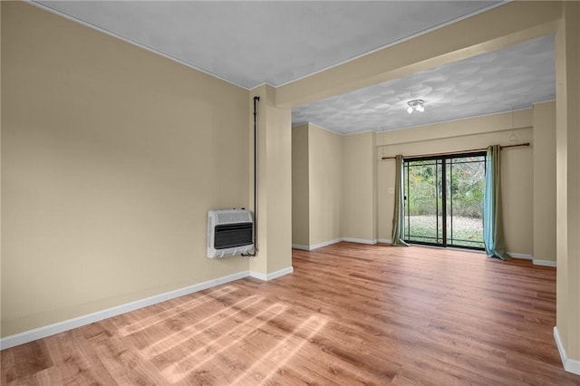 spare room featuring heating unit and light hardwood / wood-style flooring