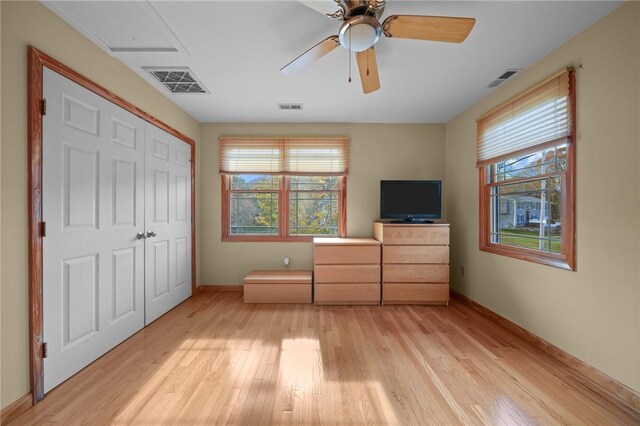 unfurnished bedroom with a closet, multiple windows, light hardwood / wood-style floors, and ceiling fan