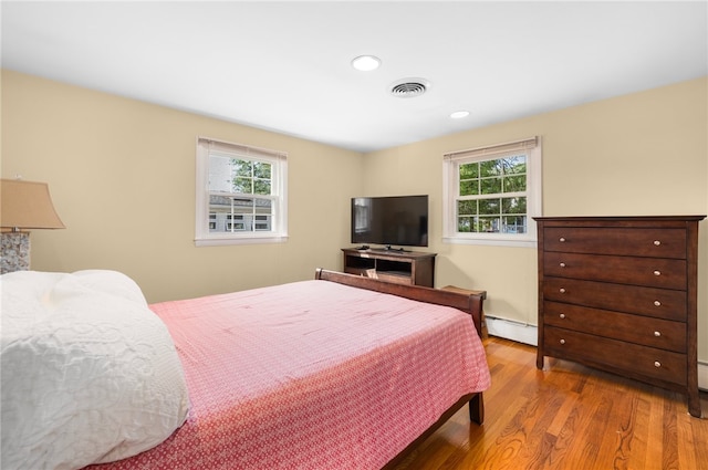 bedroom featuring light wood-type flooring and a baseboard radiator