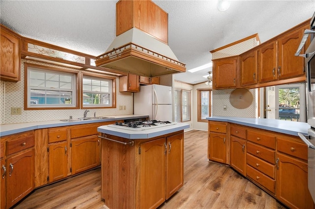 kitchen featuring a textured ceiling, sink, white appliances, and light hardwood / wood-style flooring