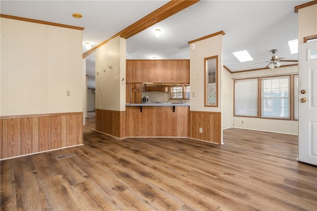 kitchen featuring ornamental molding, kitchen peninsula, dark wood-type flooring, and a skylight