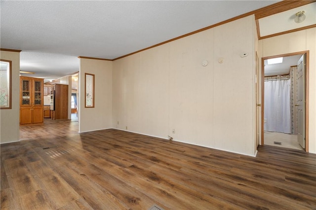 empty room with a textured ceiling, crown molding, and dark hardwood / wood-style floors