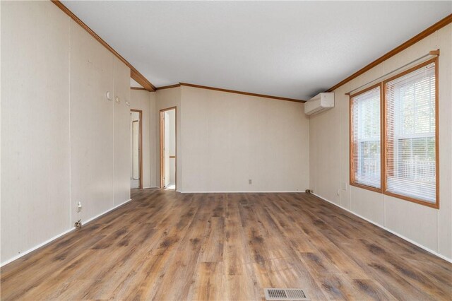 empty room featuring a wall mounted air conditioner, hardwood / wood-style floors, and ornamental molding