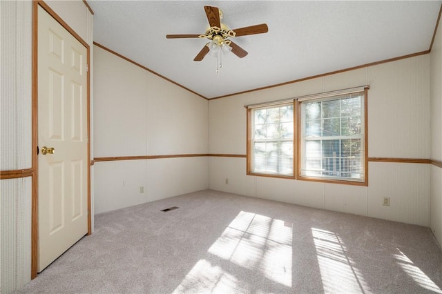 carpeted spare room featuring a textured ceiling, ceiling fan, and crown molding