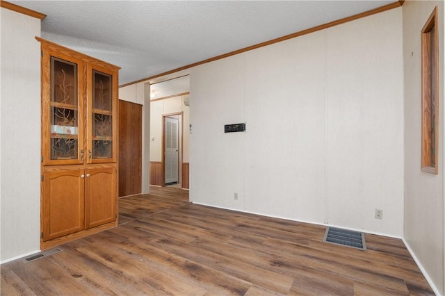 spare room featuring hardwood / wood-style flooring, crown molding, and a textured ceiling