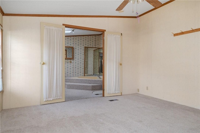 carpeted spare room featuring ceiling fan, lofted ceiling, and crown molding