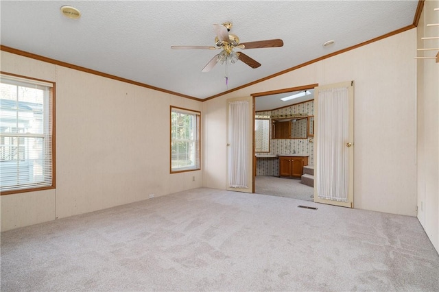 unfurnished bedroom featuring multiple windows, crown molding, light colored carpet, and vaulted ceiling