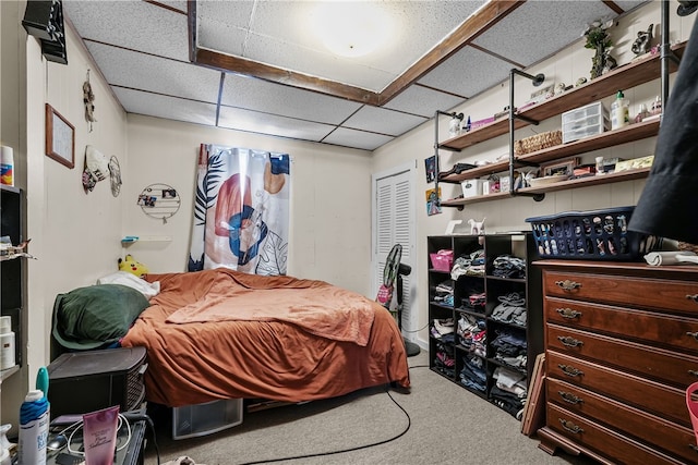 carpeted bedroom featuring a paneled ceiling and a closet