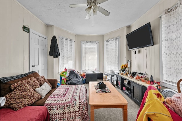 living room with carpet flooring, crown molding, ceiling fan, and a textured ceiling