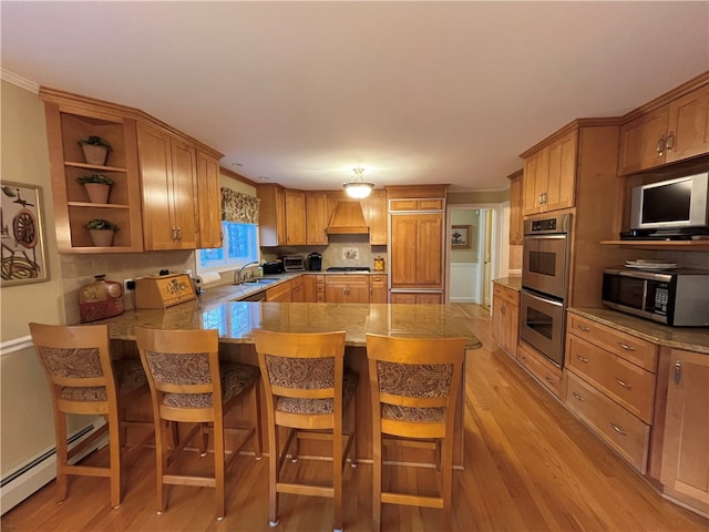 kitchen featuring a breakfast bar, custom range hood, stainless steel appliances, sink, and light hardwood / wood-style flooring