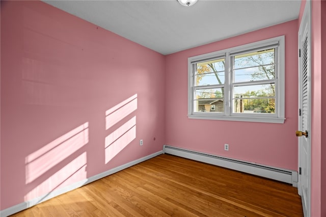 empty room featuring baseboard heating and hardwood / wood-style flooring