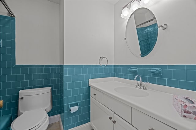 bathroom with a shower, vanity, toilet, and tile walls