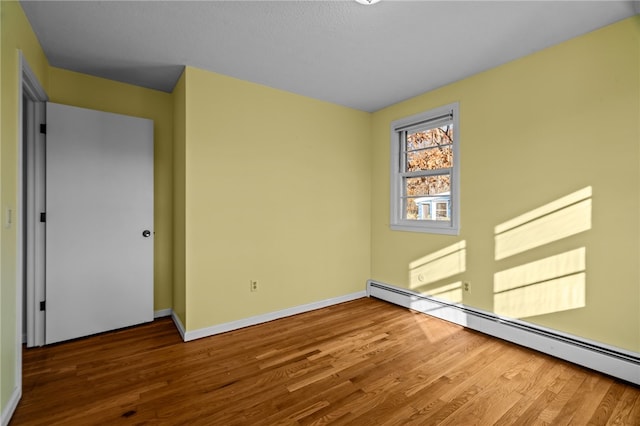 spare room with hardwood / wood-style floors and a baseboard radiator