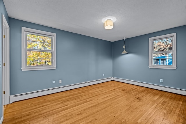 unfurnished room featuring baseboard heating, light hardwood / wood-style flooring, and a textured ceiling