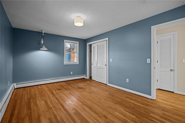 interior space featuring light hardwood / wood-style floors, baseboard heating, and a textured ceiling