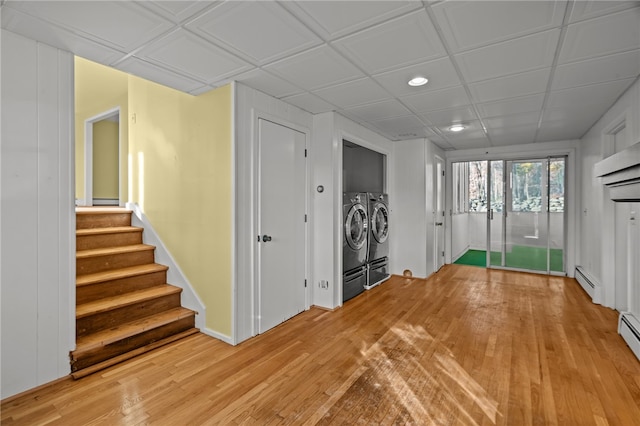 interior space with light wood-type flooring, baseboard heating, and washing machine and dryer