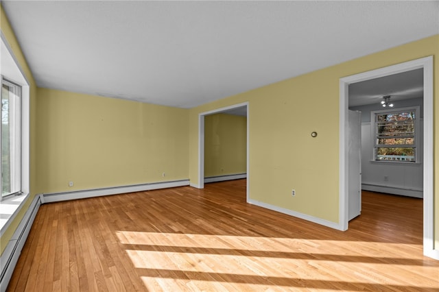 spare room featuring a baseboard heating unit and light wood-type flooring