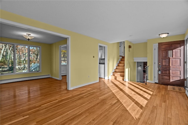 unfurnished living room with light hardwood / wood-style floors and a baseboard heating unit