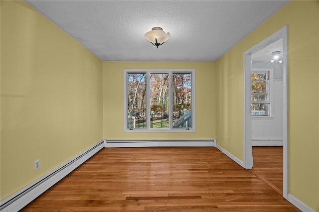 unfurnished dining area featuring baseboard heating, a textured ceiling, and light wood-type flooring